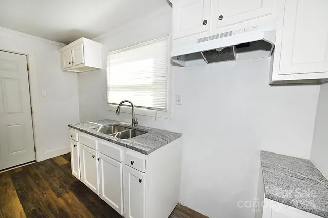 a kitchen with white cabinets and sink