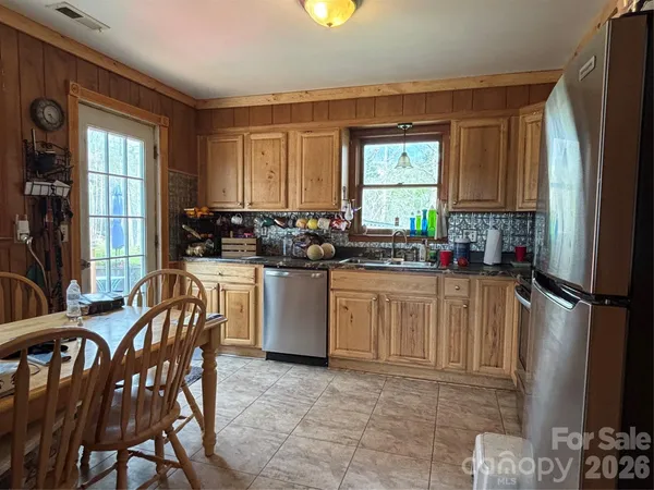 a kitchen with a refrigerator a stove a sink cabinetry and a dining table