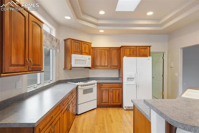 a kitchen with stainless steel appliances granite countertop a refrigerator a stove and a sink with wooden floor