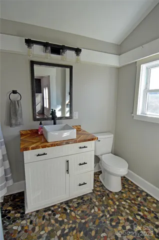a bathroom with a granite countertop sink toilet and mirror
