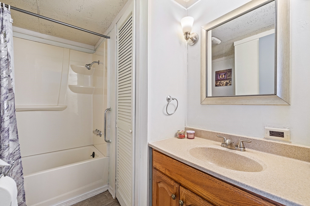 365 Main Street, Unit 3 Sturbridge, MA 01566 - Photo 17 of 20 a bathroom with a granite countertop sink a mirror a shower and a bathtub