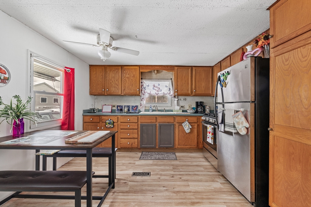 365 Main Street, Unit 3 Sturbridge, MA 01566 - Photo 7 of 20 a kitchen with stainless steel appliances granite countertop a refrigerator a sink dishwasher a stove and white countertops with wooden floor