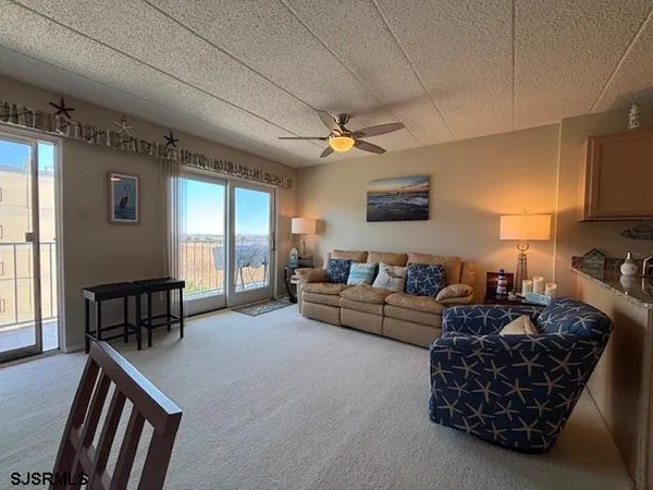 a living room with stainless steel appliances furniture a fireplace and a open kitchen