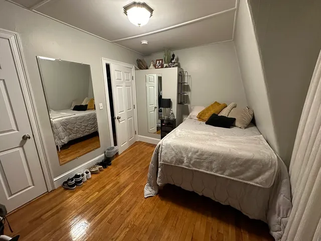 a bedroom with a bed and a mirror on the dresser