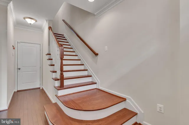 a view of staircase with wooden floor and white walls