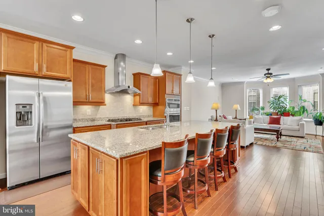 a kitchen with stainless steel appliances granite countertop a kitchen island a stove a sink a oven a dining table and chairs with wooden floor