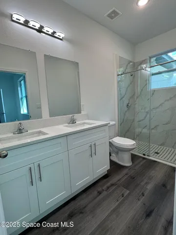 a spacious bathroom with a double vanity sink a toilet and a mirror