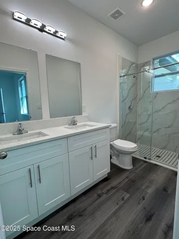 a spacious bathroom with a double vanity sink a toilet and a mirror