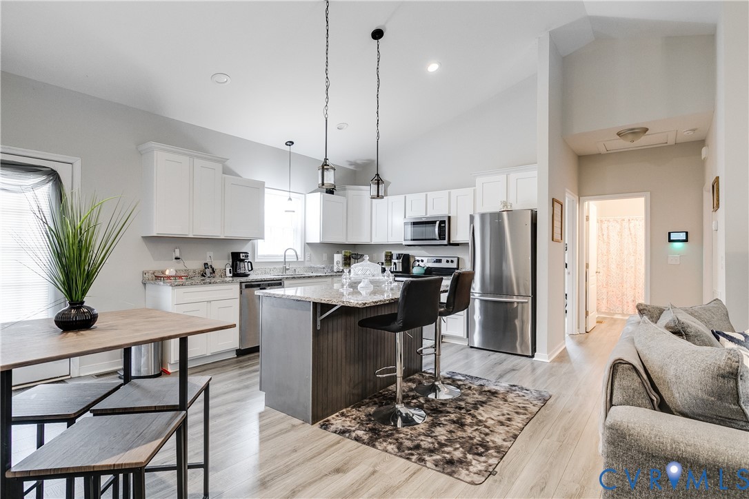 10525 Amelia Springs Road Jetersville, VA 23083 - Photo 19 of 25 a kitchen with stainless steel appliances granite countertop a refrigerator a stove a sink a dining table and chairs with wooden floor