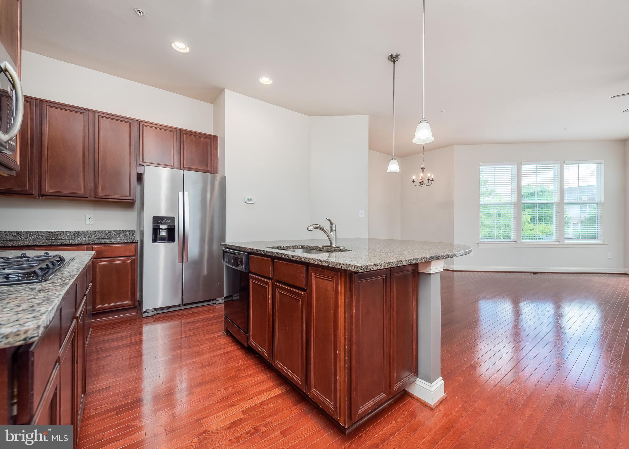 9830 Garden Ranges Laurel, MD 20723 - Photo 3 of 34 a kitchen with stainless steel appliances granite countertop wooden floors wooden cabinets a center island and a window