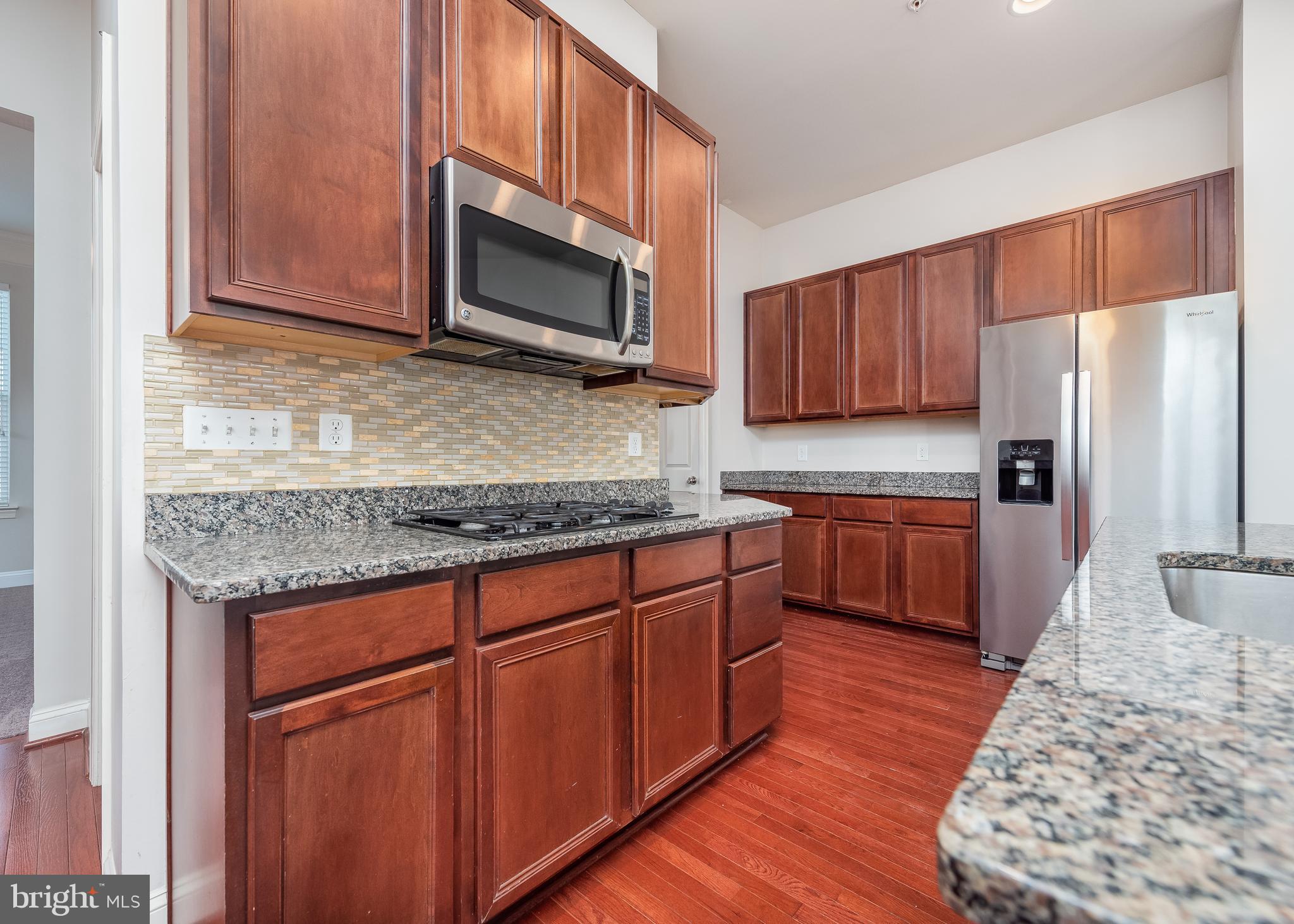 9830 Garden Ranges Laurel, MD 20723 - Photo 34 of 34 a kitchen with stainless steel appliances granite countertop a sink stove microwave and refrigerator
