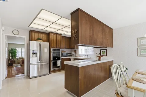 a kitchen with stainless steel appliances granite countertop a refrigerator stove top oven and sink