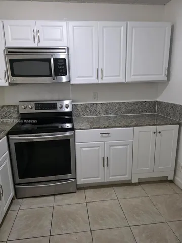 a kitchen with granite countertop white cabinets and stainless steel appliances