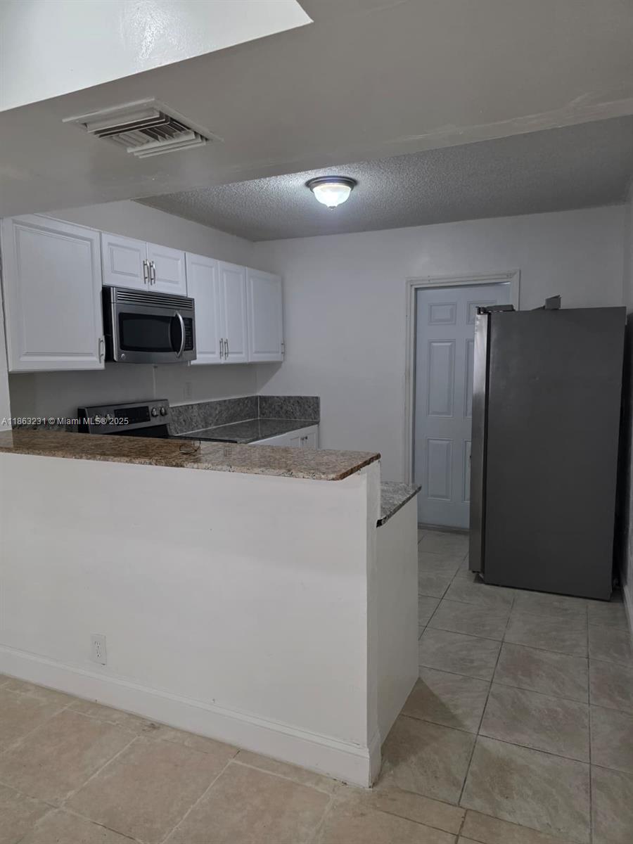 1206 Seaview, Unit 1206 North Lauderdale, FL 33068 - Photo 5 of 17 a kitchen with stainless steel appliances granite countertop a refrigerator and a stove