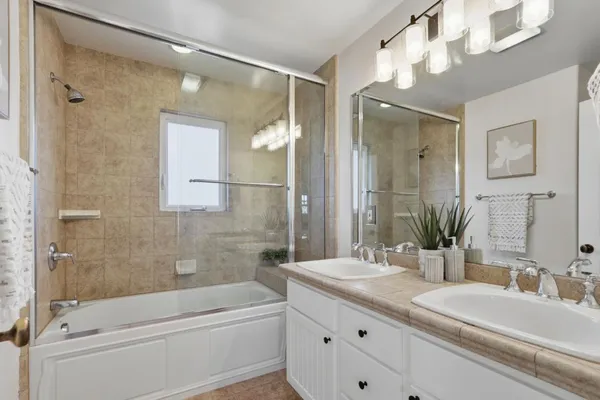 a bathroom with a granite countertop sink a mirror a bathtub and shower