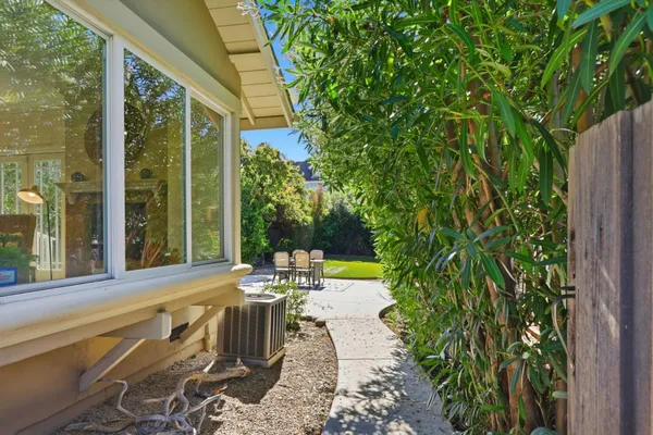 a view of a patio with table and chairs potted plants and floor to ceiling window