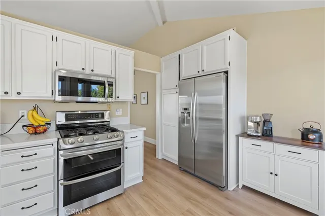 a kitchen with cabinets stainless steel appliances and wooden floor