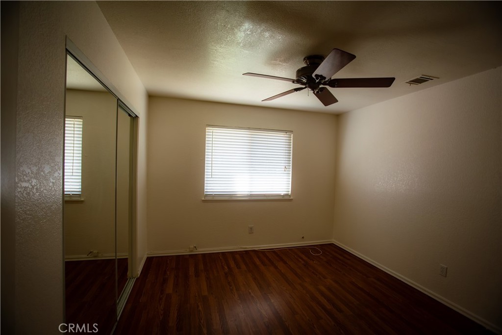 21090 Lone Eagle Road Apple Valley, CA 92308 - Photo 6 of 11 an empty room with wooden floor fan and windows