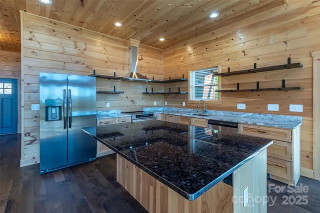 a kitchen with stainless steel appliances granite countertop a sink a stove and a wooden floors