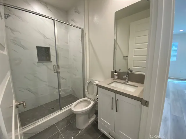a bathroom with a granite countertop sink a toilet and shower