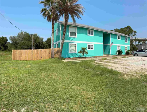a view of a house with a yard and a large tree