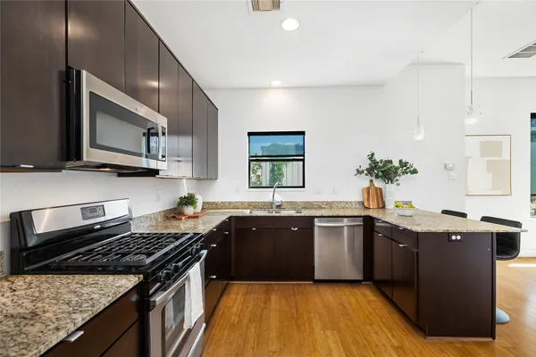 a kitchen with granite countertop a refrigerator a stove and wooden floor