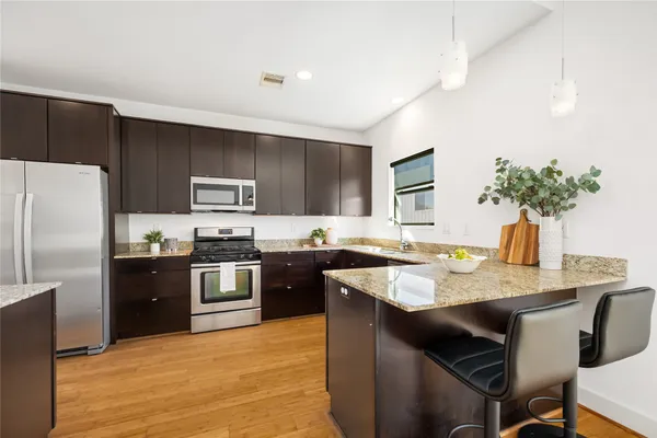 a kitchen with stainless steel appliances granite countertop a sink dishwasher stove refrigerator and microwave