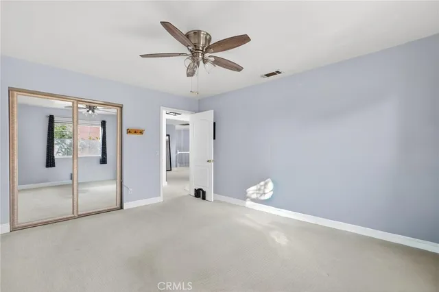 an empty room with windows and chandelier fan