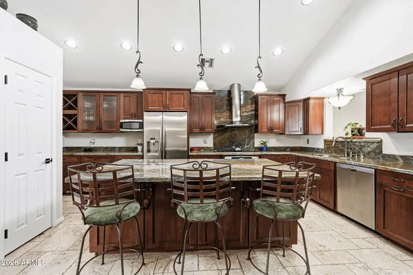a kitchen with stainless steel appliances a sink a stove a center island and chairs