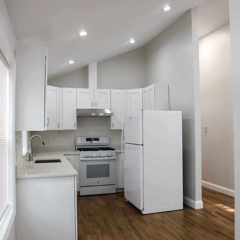 598 School Street, Unit REAR ADU Lowell, MA 01851 - Photo 21 of 42 a kitchen with a refrigerator a stove top oven a sink and cabinets