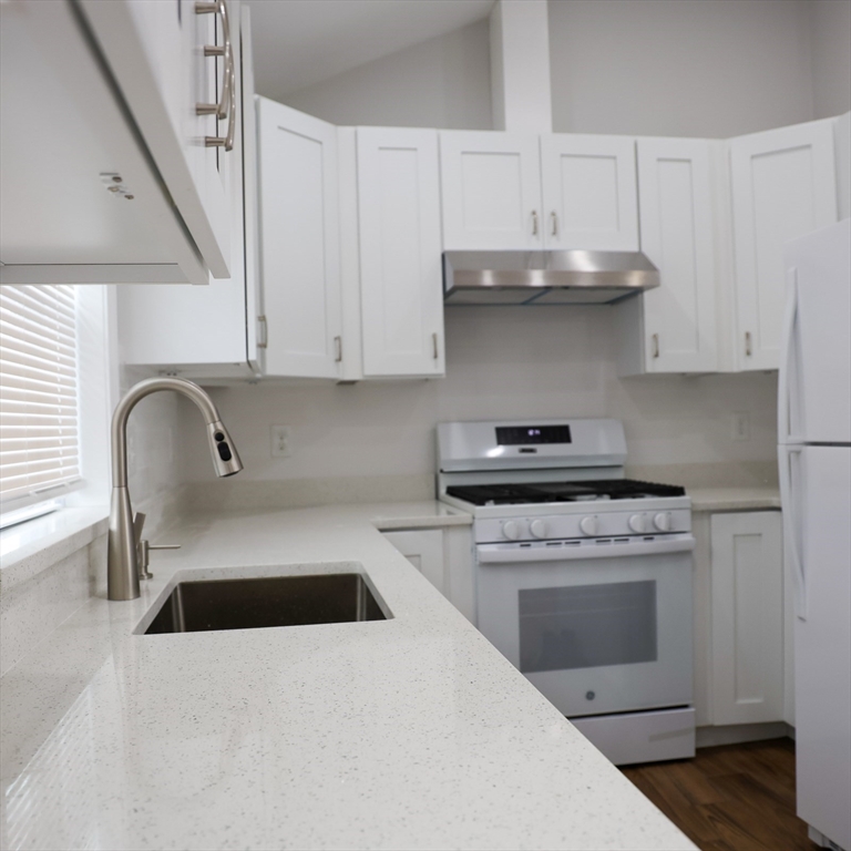 598 School Street, Unit REAR ADU Lowell, MA 01851 - Photo 23 of 42 a kitchen with granite countertop a stove top oven a sink and dishwasher
