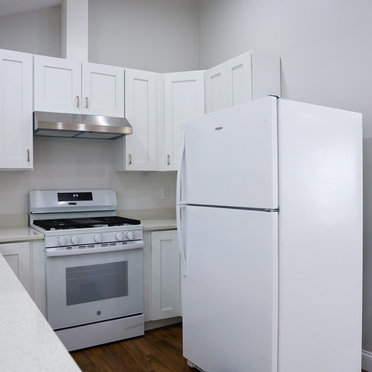 598 School Street, Unit REAR ADU Lowell, MA 01851 - Photo 26 of 42 a white refrigerator freezer and a stove sitting inside of a kitchen with granite countertop cabinets