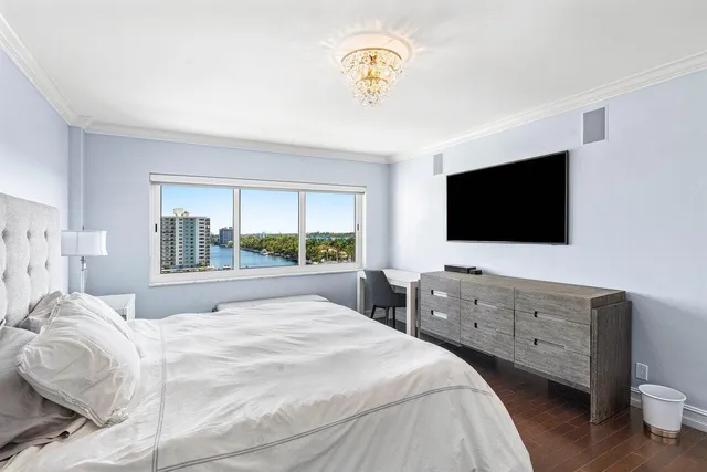 a bedroom with a large bed and a flat tv screen on dresser