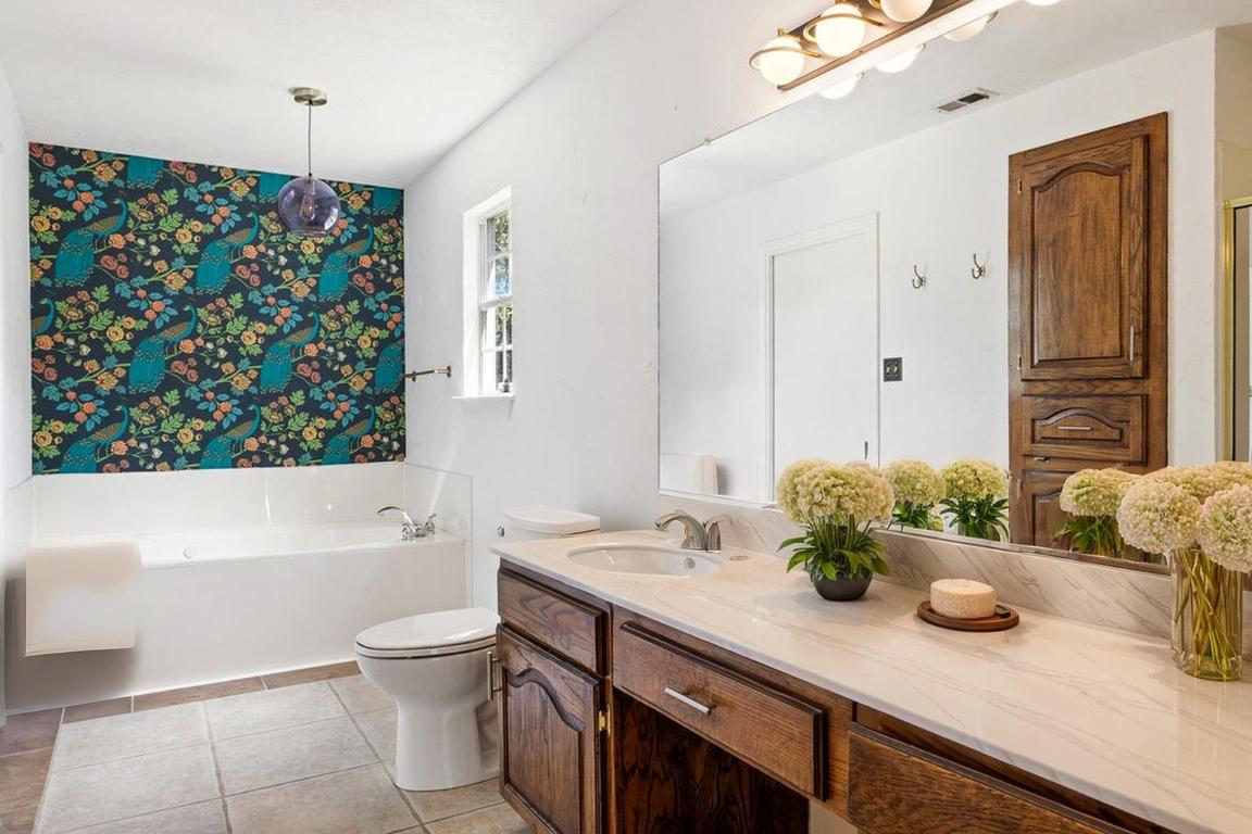 2412 Jones Road Austin, TX 78745 - Photo 13 of 40 a bathroom with a granite countertop sink a toilet a mirror and shower