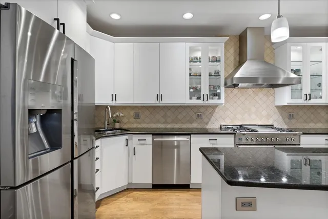 a kitchen with stainless steel appliances granite countertop a sink a stove and a refrigerator