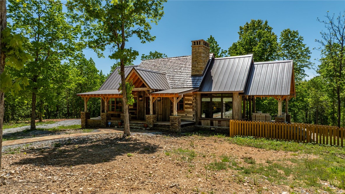 425 Barnhardt Road Timbo, AR 72680 - Photo 8 of 60 Rustic-style home featuring a mixed-material exterior, a stone chimney, and a wooden picket fence