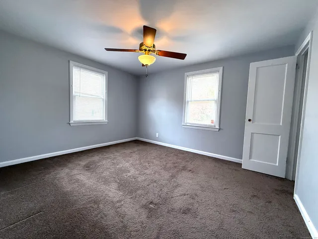 an empty room with windows and chandelier fan