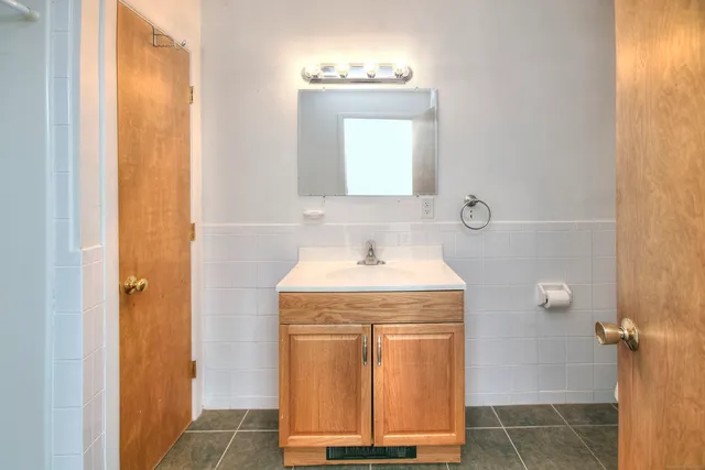 a bathroom with a granite countertop sink a mirror and a shower