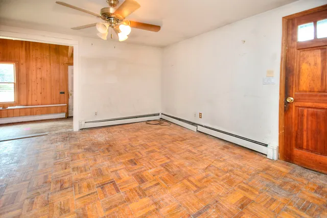 an empty room with a chandelier fan and windows