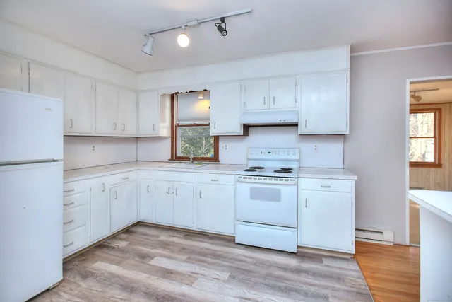 a kitchen with granite countertop white cabinets and white appliances