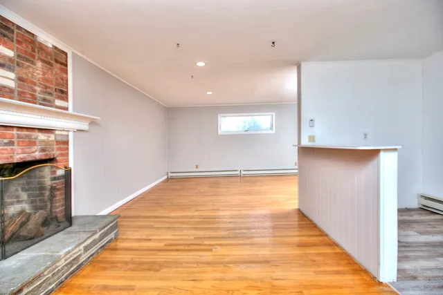a view of an empty room with wooden floor and a fireplace