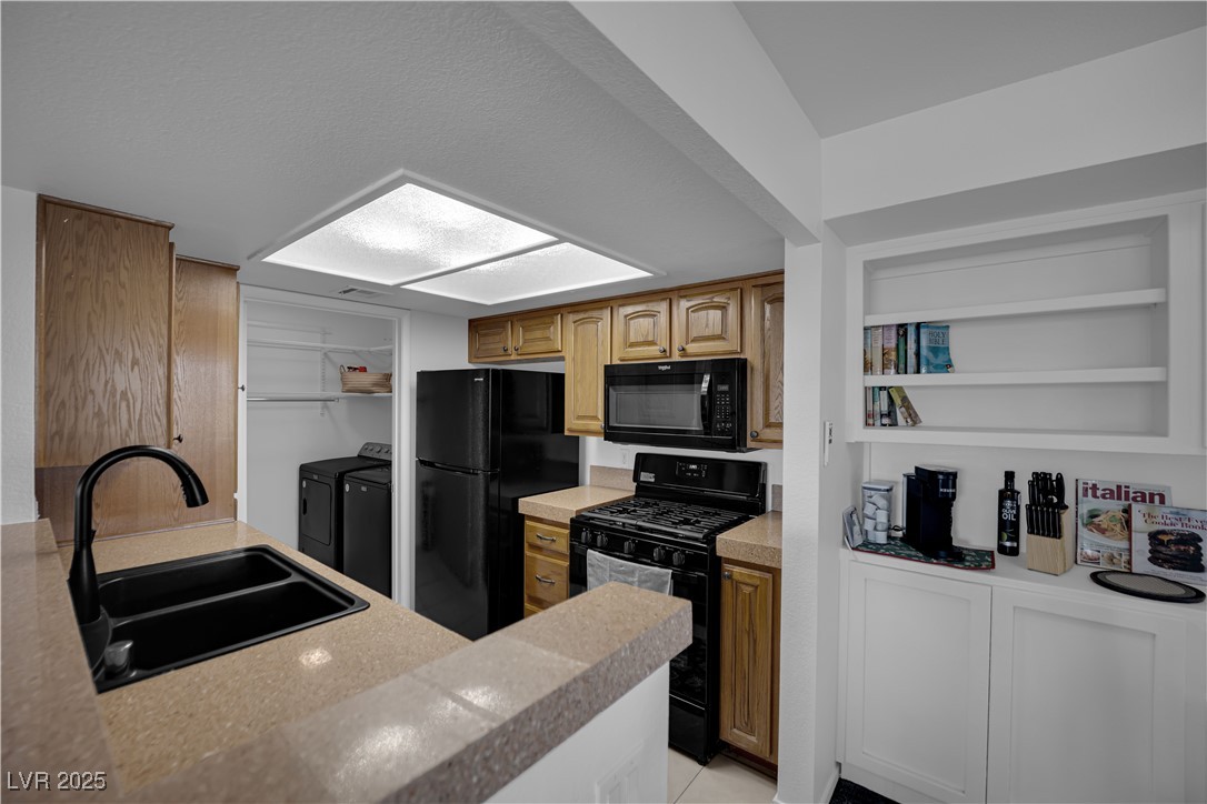 1909 Mountain Hills Court, Unit 205 Las Vegas, NV 89128 - Photo 20 of 34 Kitchen with black appliances, light countertops, washer and dryer, and a textured ceiling