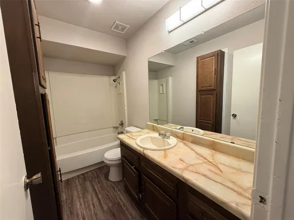 a bathroom with a granite countertop sink a toilet a large mirror and shower
