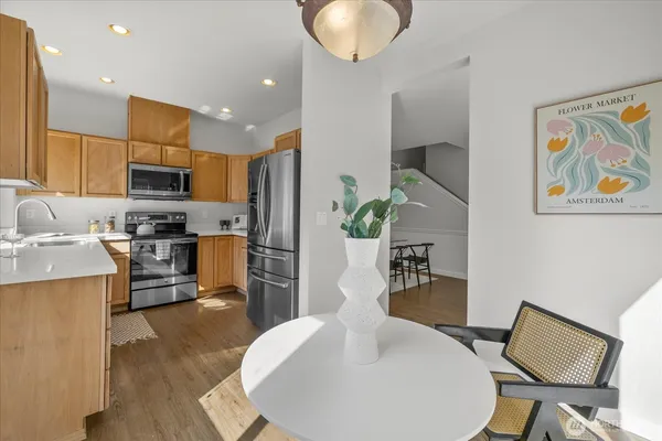 a kitchen with stainless steel appliances granite countertop a stove top oven a sink a dining table and chairs with wooden floor