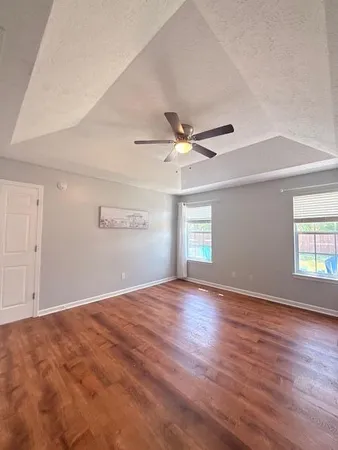 a view of empty room with wooden floor and fan