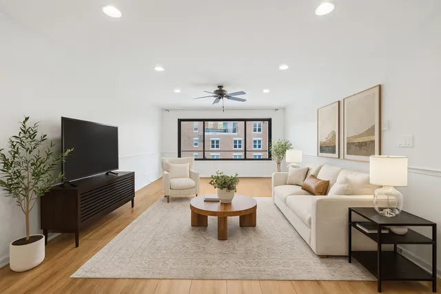 a living room with furniture a flat screen tv and a potted plant