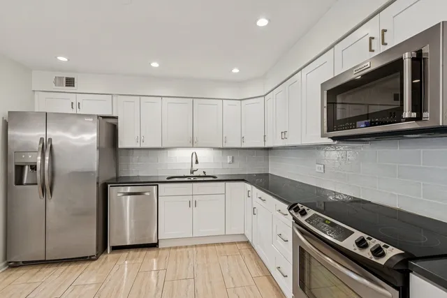 a kitchen with stainless steel appliances granite countertop a stove a sink and a microwave