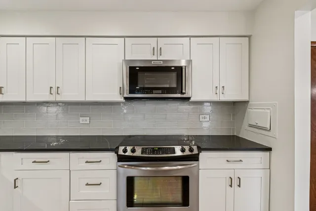 a kitchen with granite countertop white cabinets and stainless steel appliances
