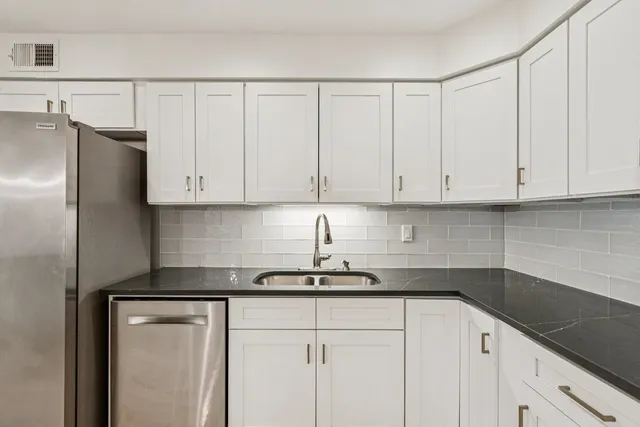 a kitchen with granite countertop white cabinets and a stainless steel appliances