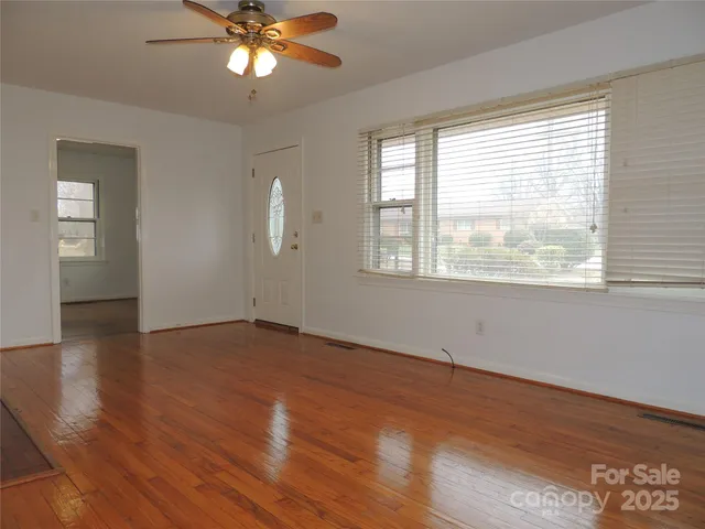 a view of an empty room with wooden floor and a window